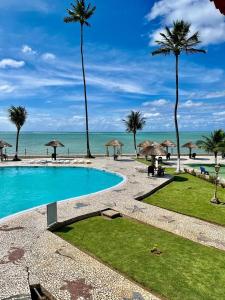 una piscina junto a una playa con palmeras en Flats Privé Village Galés, en Maragogi