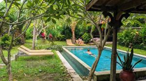 a person swimming in a pool in a backyard at Room #5 Mari Posa Cottage in Badung +5 photos