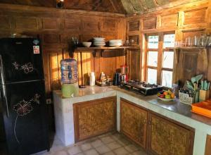 a kitchen with wooden cabinets and a black refrigerator at Room #5 Mari Posa Cottage in Badung