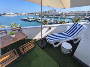 a balcony with two benches and a table and an umbrella at Port PENTHOUSE in Tarragona