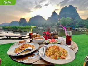 For You Ninh Binh Boutique في نينه بينه: طاولة خشبية عليها صحون طعام ومشروبات