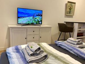 a bedroom with towels on a bed and a flat screen tv at NEU wunderschöne Goldstadt Suite am Schlössle Zentrum Pforzheim in Pforzheim