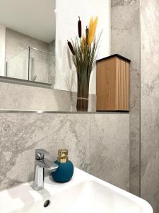 a bathroom with a sink and a vase with flowers at NEU wunderschöne Goldstadt Suite am Schlössle Zentrum Pforzheim in Pforzheim