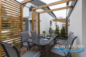 a dining room with a table and chairs on a patio at Domek w Baltic Natur Park Komfortowy 2 sypialnie klima alpaki mnóstwo atrakcji by DG in Niechorze +66 photos