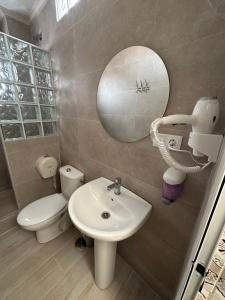 un bagno con lavandino, WC e specchio di Hostal Gutierrez a Ceuta