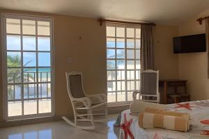 a bedroom with two beds and two chairs and windows at Villa del Mar, un espacio funcional y bien ubicado in Progreso