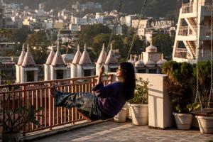 a woman sitting on a balcony looking at a city at LiveAway Rishikesh, Laxman Jhula by PACK in Rishīkesh