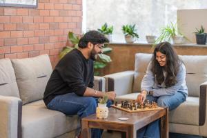 a man and woman playing chess in a living room at LiveAway Rishikesh, Laxman Jhula by PACK in Rishīkesh +99 photos