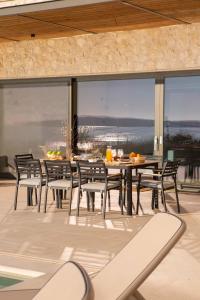 a dining room with a table and chairs and windows at Amber by the sea in Évyiros