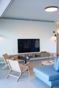 a living room with a tv and chairs and a couch at Amber by the sea in Évyiros