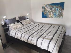 Una cama en un dormitorio con un cuadro en la pared. en L'atelier, chalet proche lac et océan à Hourtin, en Hourtin