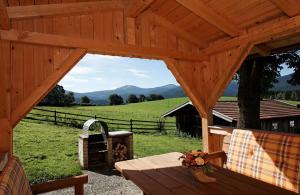 a wooden pavilion with a table and a view of a field at Ferienwohnungen am Arber - Haus Osser - in Lohberg +5 photos