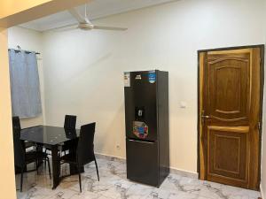 a dining room with a table and a black refrigerator at Premium House Kouritenga ISPP in Ouagadougou