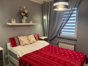 a bedroom with a bed with a red blanket and a window at Ekskluzywny Apartament Joanna w centrum Bochni in Bochnia