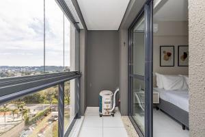 a bedroom with a balcony with a bed and a window at Edifício Champagnat Office in Curitiba