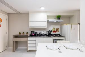 a kitchen with white cabinets and a white table with wine glasses at Edifício Champagnat Office in Curitiba +12 photos