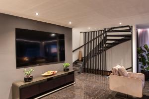 a living room with a large television and a chair at Villa Tauris in Emmetten