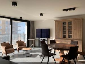 ein Wohnzimmer mit Tisch und Stühlen und einem Fernseher in der Unterkunft O'Sea ref 104,105,106 in Koksijde
