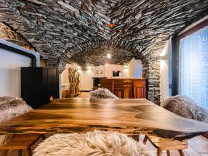 una mesa de madera en una habitación con una pared de piedra en La Volta di Champoluc - Poluc Apartments Monolocale, en Champoluc