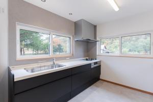 a kitchen with a sink and two windows at Ubaku Villa 宇莫別荘 in Biei