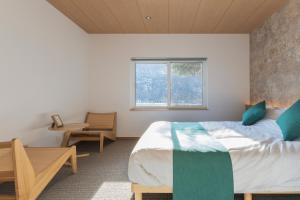 a bedroom with a bed and a table and a window at Ubaku Villa 宇莫別荘 in Biei