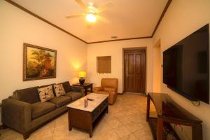 Veranda 3G 2 bedr 2 bath في Isla Herradura: غرفة معيشة مع أريكة وتلفزيون بشاشة مسطحة