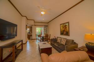 Veranda 3G 2 bedr 2 bath في Isla Herradura: غرفة معيشة مع أريكة وتلفزيون