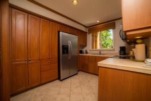 Veranda 3G 2 bedr 2 bath في Isla Herradura: مطبخ مع خزائن خشبية وثلاجة من الفولاذ المقاوم للصدأ