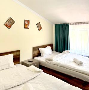 two beds in a room with green curtains at GRAND Hotel in Almaty +5 photos