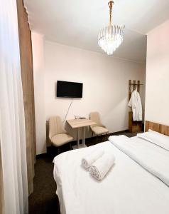 a bedroom with a bed and a desk and a tv at GRAND Hotel in Almaty