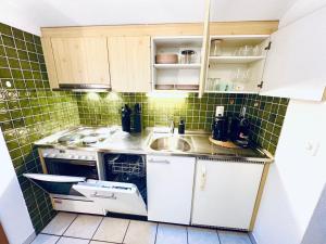 a small kitchen with white cabinets and green tiles at Bergtraum Suite in Kandersteg +27 photos