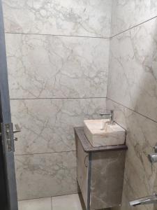 een badkamer met een wastafel en een marmeren muur bij Aarav Home in Indore +2 foto's