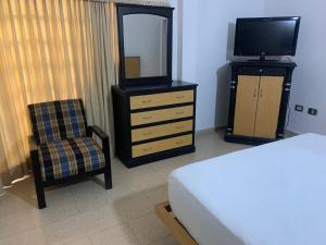 a bedroom with a dresser with a television and a chair at Hotel Platinum Boutique in Montería