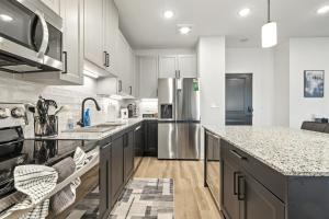 a large kitchen with white cabinets and granite counter tops at IRIE Living Brand New Lux 2BR Min Grand Park in Westfield