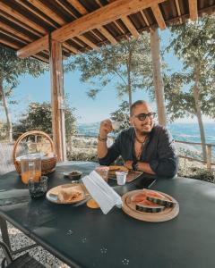 a man sitting at a table with a plate of food at Glamping & country house Marche Nascoste Gualdo in San Girolamo di Sopra