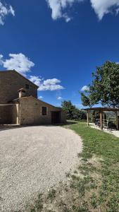 a building with a gravel driveway in front of it at Glamping & country house Marche Nascoste Gualdo in San Girolamo di Sopra
