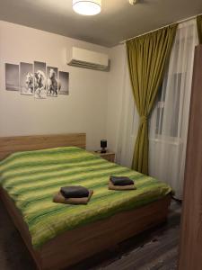 a bedroom with a green bed with two towels on it at Апартамент Димана in Hisarya