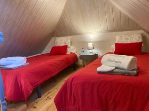 two beds in a attic room with red sheets at Escapade Bretonne in Rospez