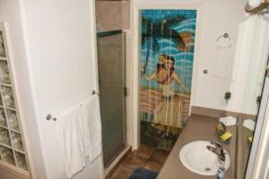 a bathroom with a sink and a shower with a painting at Hale Hualalai in Kailua-Kona