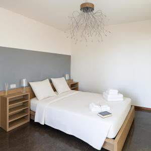 a bedroom with a large white bed and a chandelier at Appartamento in Villa Monaco in Mosciano SantʼAngelo