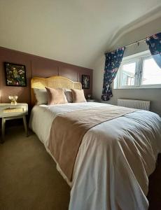 a bedroom with a large bed and a window at Daisy Cottage - Framlingham in Framlingham