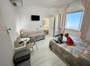 two children sitting on beds in a hotel room at Hotel Belvedere in Sottomarina