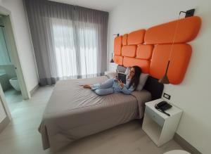 a woman sitting on a bed reading a book at Hotel Belvedere in Sottomarina