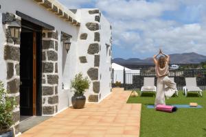 een vrouw die yoga doet op het dak van een huis bij Spacious Private Villa up to 16 - Authentic Yaiza - Volcano, Timanfaya park, Bodega & South Beaches - Heated Pool - Game Room - Charcoal grill in Yaiza