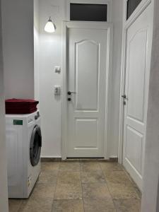 una lavanderia con porta bianca e lavatrice di Amy's Home a Craiova