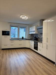 a kitchen with white cabinets and a wooden floor at Modern apartment with feel-good factor in Gravenwerth