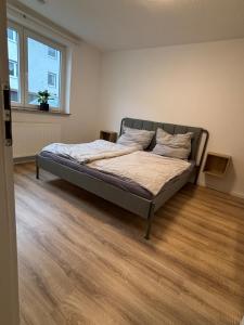 a bed in a bedroom with a wooden floor at Modern apartment with feel-good factor in Gravenwerth