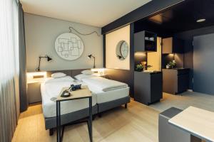 a hotel room with two beds and a table at harry's home Zürich-Limmattal in Spreitenbach