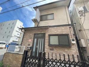 a brick house with a black door and a fence at koto KAWASAKI in Kawasaki