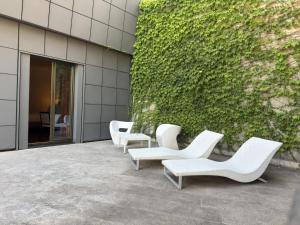 a group of white chairs sitting next to a building at Ariha Hotel Cosenza in Cosenza
